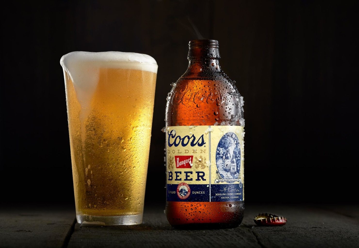 Golden beer poured into glass with foam head beside branded bottle photographed for commercial alcohol marketing