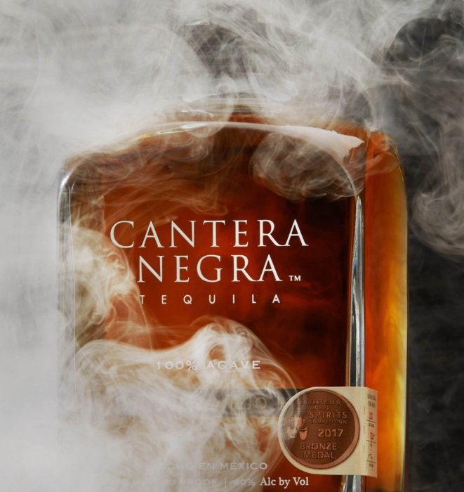 Smoke swirling around a bottle of dark tequila