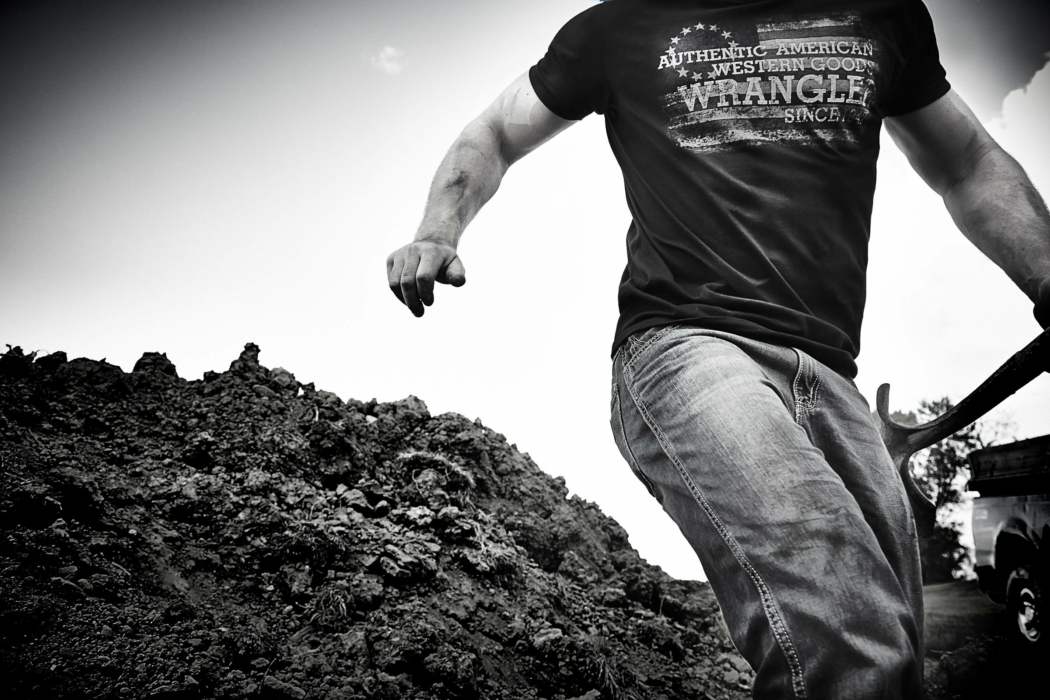 Person walking across dirt wearing a Wrangler shirt in a rugged outdoor setting