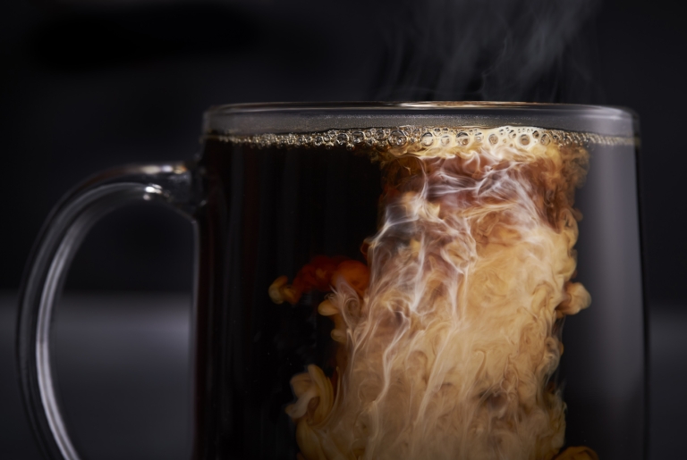 Coffee in glass mug with cream swirling captured using high-speed commercial glass photography