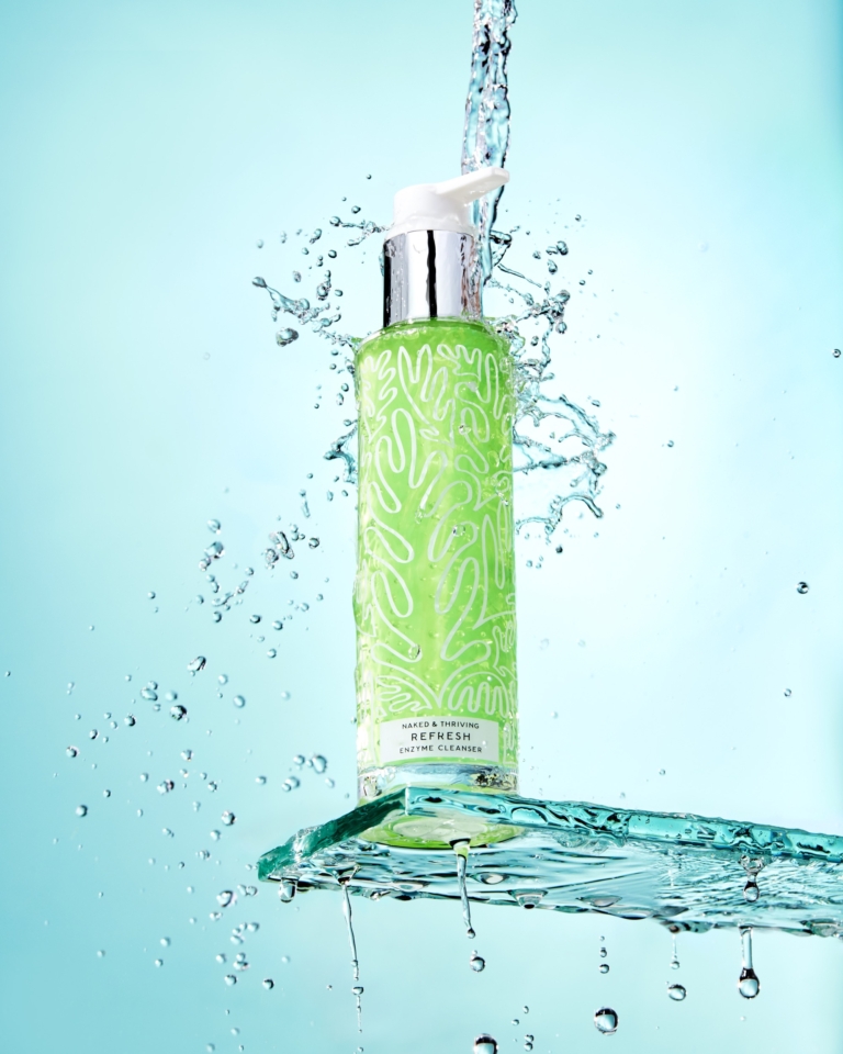 Naked and Thriving Cleanser bottle captured with water splash in commercial skincare photography