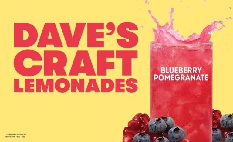 Wendy's Dave's Craft Lemonade blueberry pomegranate in a clear cup with fresh blueberries and raspberries on a yellow background