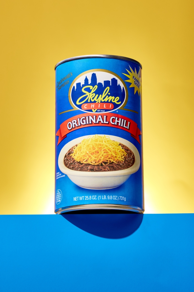 Can of chili photographed against a yellow and blue background.