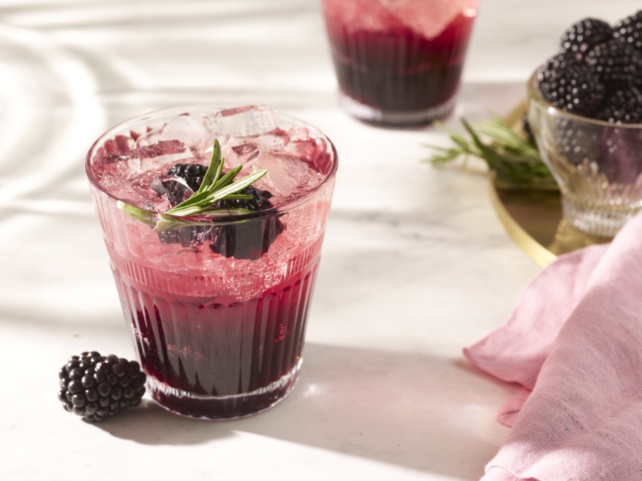 a glass of drink with ice and berries