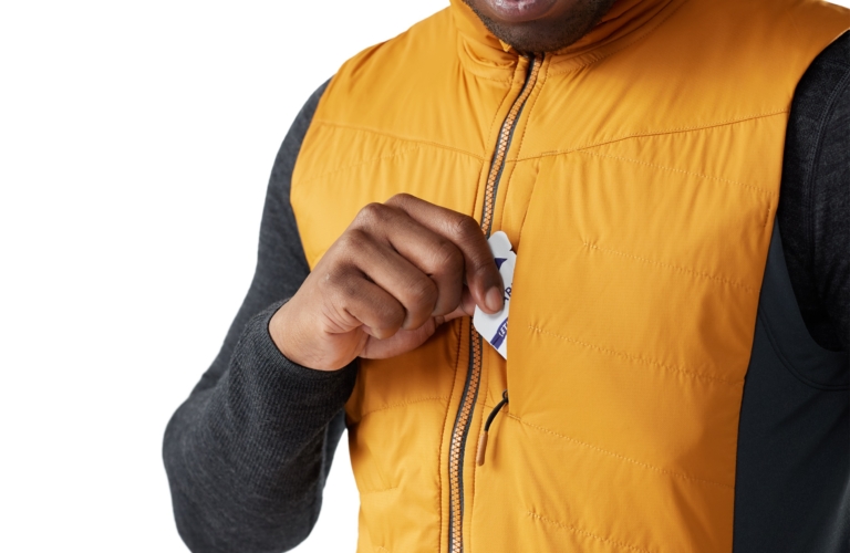Close-up of man zipping a yellow insulated vest showing garment detail and texture