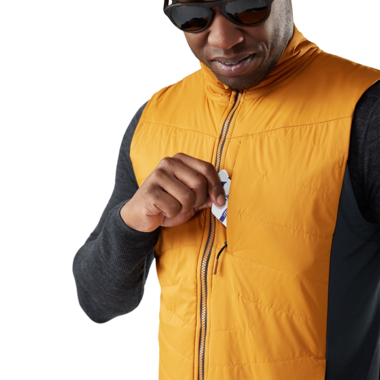 Close-up of man zipping a yellow insulated vest showing garment detail and texture