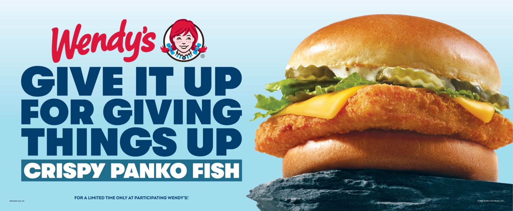 Close-up of Wendy’s Panko Fish Sandwich with lettuce, cheese, and a golden crispy fillet on a toasted bun against a blue background.