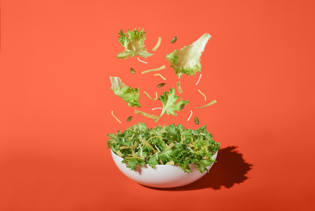 a bowl of salad with lettuce falling into it