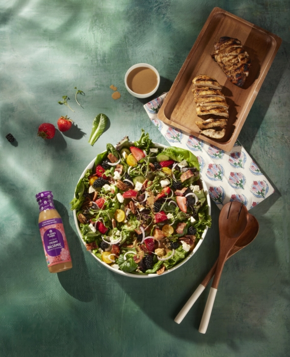 a bowl of salad with a fork and spoon next to a plate of meat