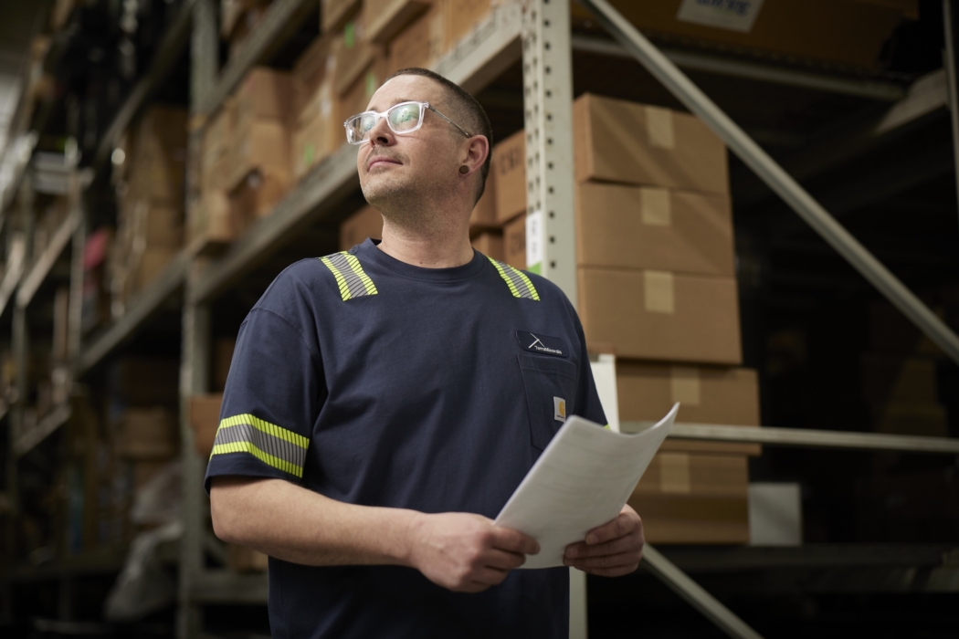 a man holding a paper in a warehouse, Cintas, construction, workplace, jobsite, on location