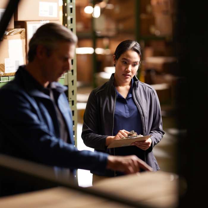 a woman holding a clipboard and a man standing in a warehouse, Cintas, construction, workplace, jobsite, on location