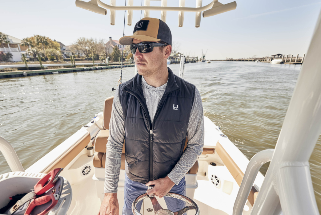 Hero shot of man wearing HUK performance apparel on a boat, captured for outdoor lifestyle and brand marketing by OMS Photography