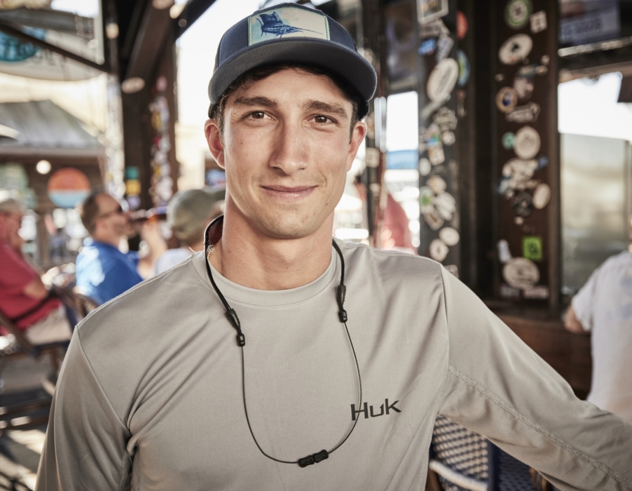 Hero shot of man wearing HUK performance apparel with modern bar-restaurant in background, captured for outdoor lifestyle and brand marketing by OMS Photography
