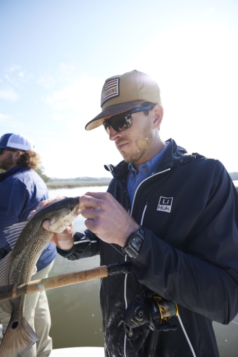 Man holding freshly caught fish while wearing HUK performance gear, captured for outdoor adventure and fishing lifestyle photography by OMS Photography