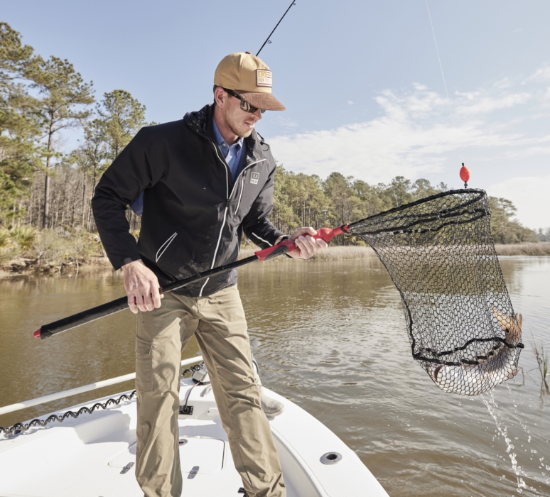 Man holding freshly caught fish while wearing HUK performance gear, captured for outdoor adventure and fishing lifestyle photography by OMS Photography