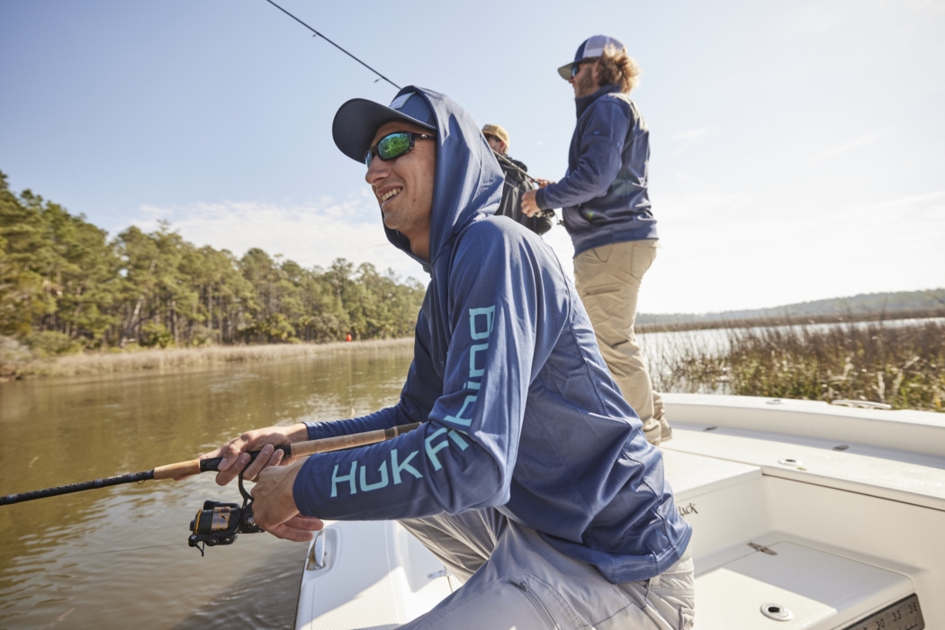 Two men wearing HUK fishing gear casting lines in outdoor setting, captured for adventure and lifestyle brand photography by OMS Photography