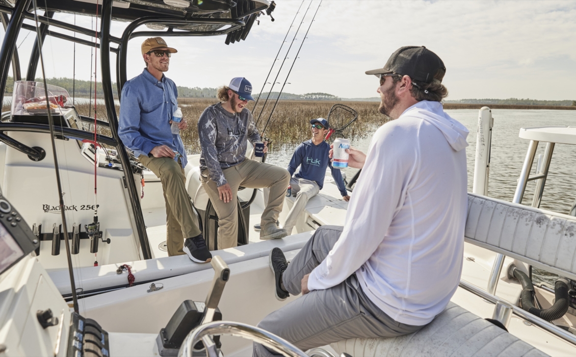 Group of men in HUK fishing gear drinking beers on a boat, captured for outdoor adventure and lifestyle brand photography by OMS Photography