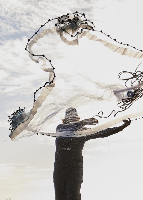 Man holding fishing net in outdoor setting, captured for adventure lifestyle and angling brand photography by OMS Photography