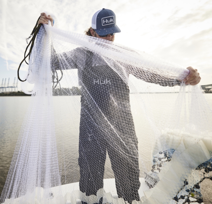 Man holding fishing net in outdoor setting, captured for adventure lifestyle and angling brand photography by OMS Photography