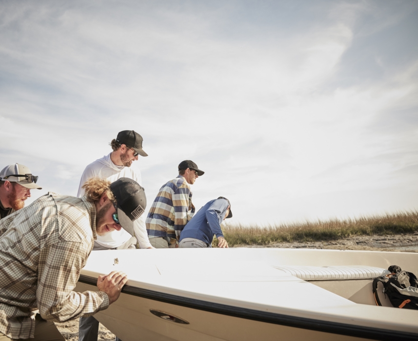 Wide shot of three anglers on a boat surrounded by open water and natural landscape, captured for outdoor lifestyle and fishing campaigns by OMS Photography