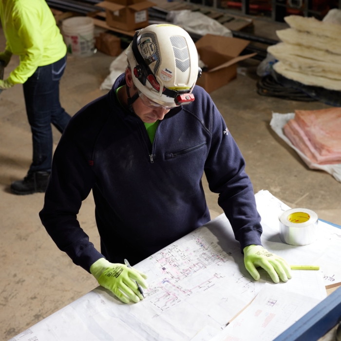 a man wearing a hard hat writing on a paper, Cintas, construction, workplace, jobsite, on location