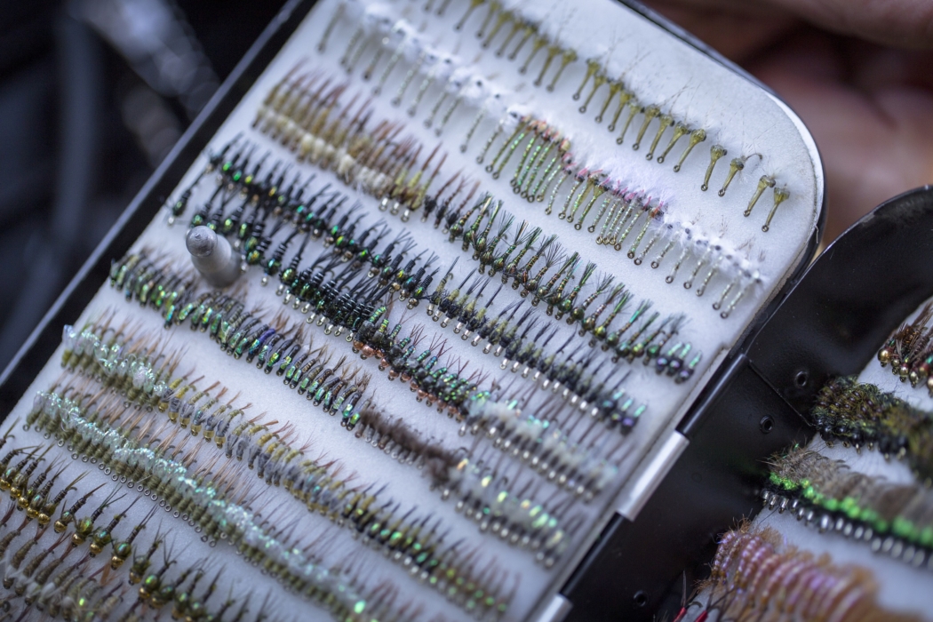 Close-up of colorful fly fishing flies arranged on tackle box, captured for outdoor adventure and angling lifestyle photography by OMS Photography