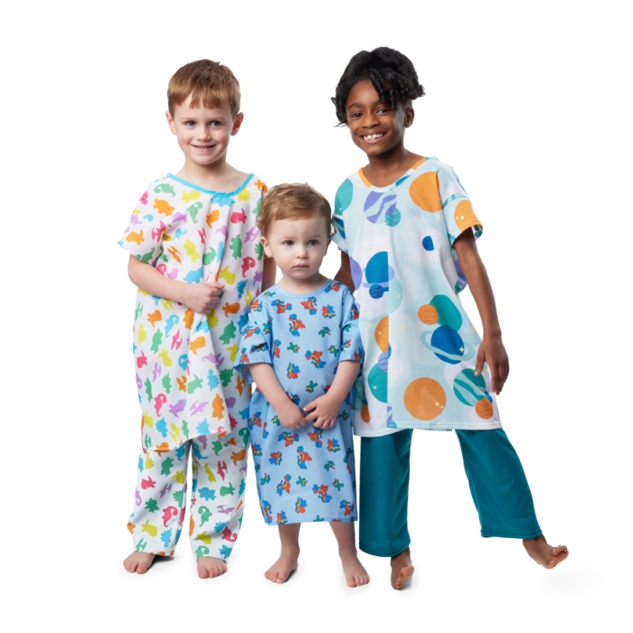 Children wearing colorful pediatric hospital gowns photographed on a white background by Marci Rhodes of OMS Photography – clean textile image showcasing fit, pattern, and comfort.