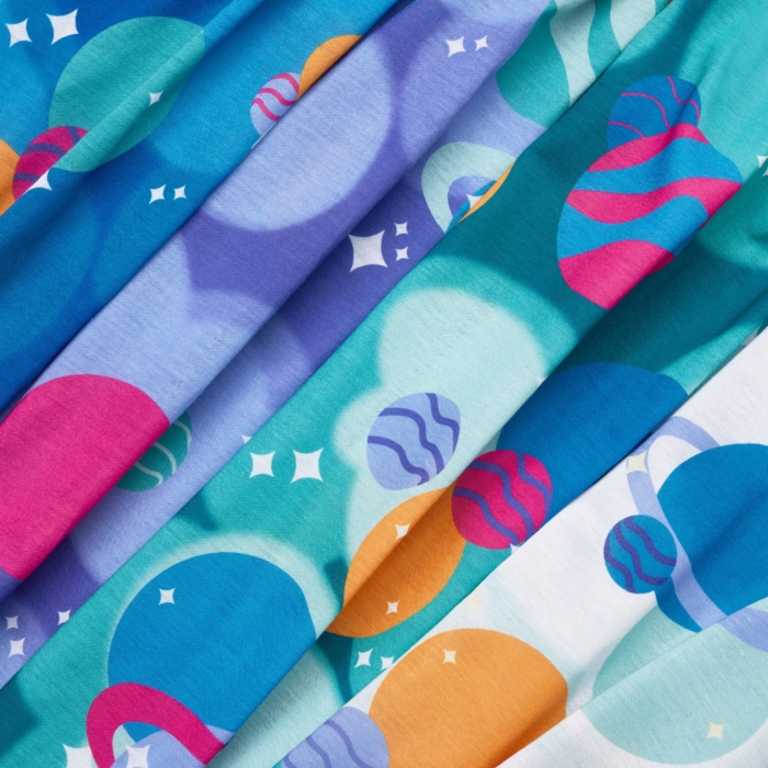 Close-up studio image of pediatric hospital gowns on white background by Marci Rhodes of OMS Photography – detailed textile shot highlighting fabric texture, stitching, and playful patterns.
