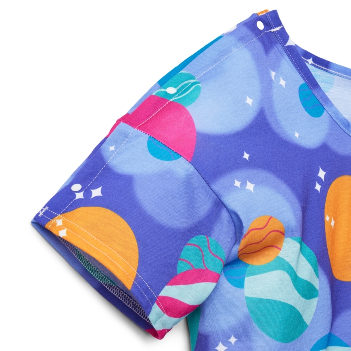 Close-up studio image of pediatric hospital gowns on white background by Marci Rhodes of OMS Photography – detailed textile shot highlighting fabric texture, stitching, and playful patterns.