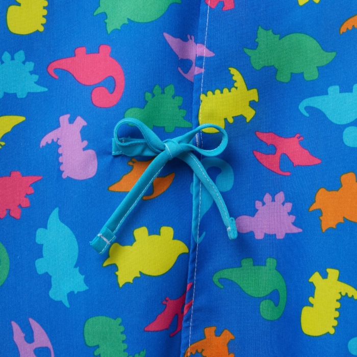 Close-up studio image of pediatric hospital gowns on white background by Marci Rhodes of OMS Photography – detailed textile shot highlighting fabric texture, stitching, and playful patterns.