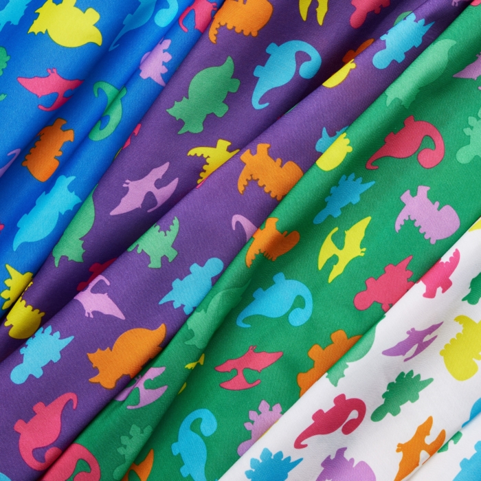 Close-up studio image of pediatric hospital gowns on white background by Marci Rhodes of OMS Photography – detailed textile shot highlighting fabric texture, stitching, and playful patterns.
