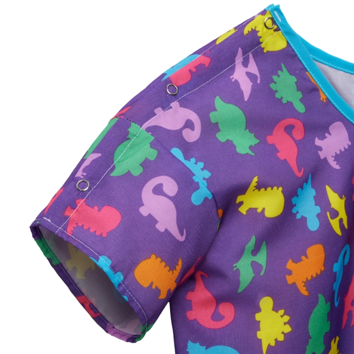 Close-up studio image of pediatric hospital gowns on white background by Marci Rhodes of OMS Photography – detailed textile shot highlighting fabric texture, stitching, and playful patterns.