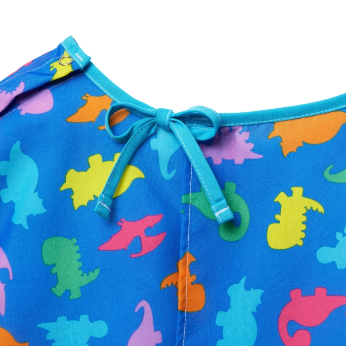 Close-up studio image of pediatric hospital gowns on white background by Marci Rhodes of OMS Photography – detailed textile shot highlighting fabric texture, stitching, and playful patterns.