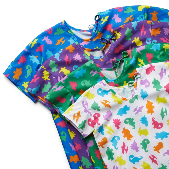 Close-up studio image of pediatric hospital gowns on white background by Marci Rhodes of OMS Photography – detailed textile shot highlighting fabric texture, stitching, and playful patterns.