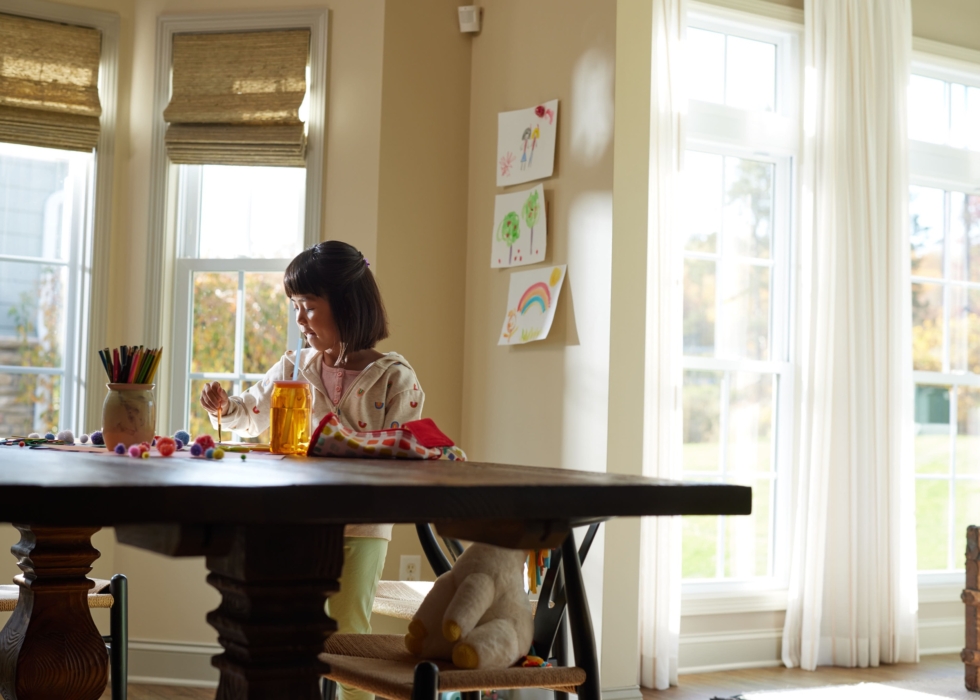 a girl sitting at a table drinking juice