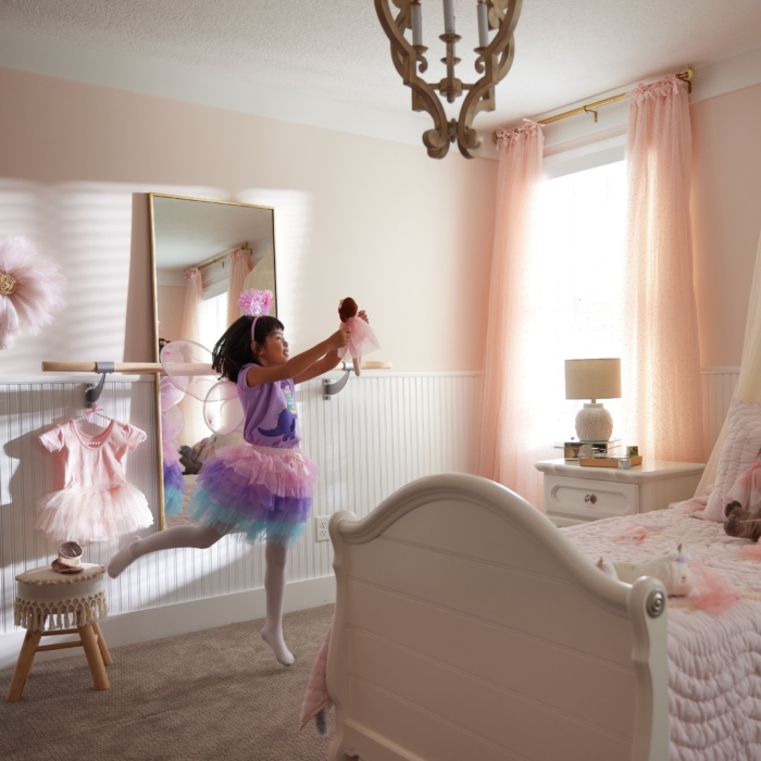 a girl in a pink tutu jumping in a bedroom