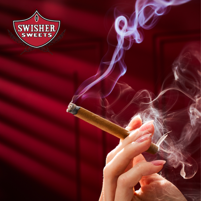 Hand holding a lit Swisher Sweets cigar with smoke billowing, captured by OMS Photography for commercial advertising and lifestyle marketing.