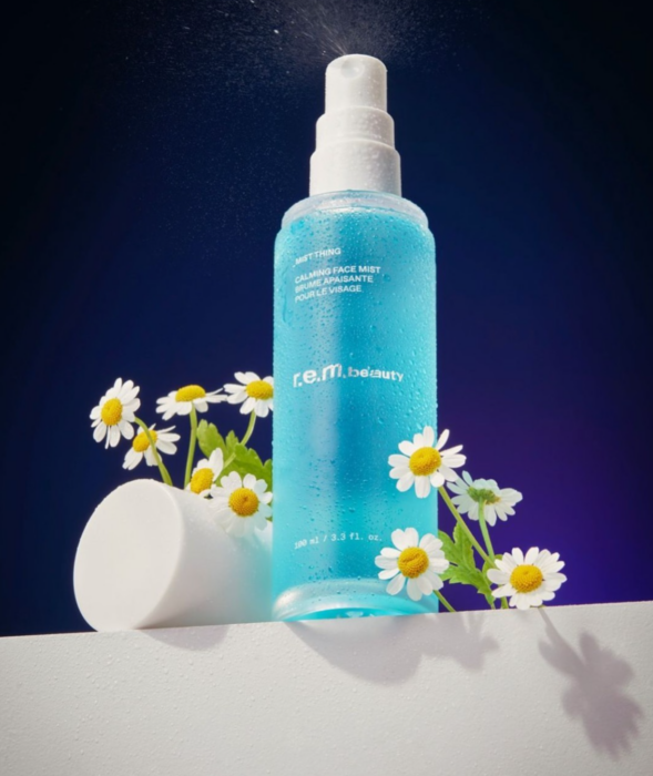 a blue spray bottle with a white cap and white cap with white flowers