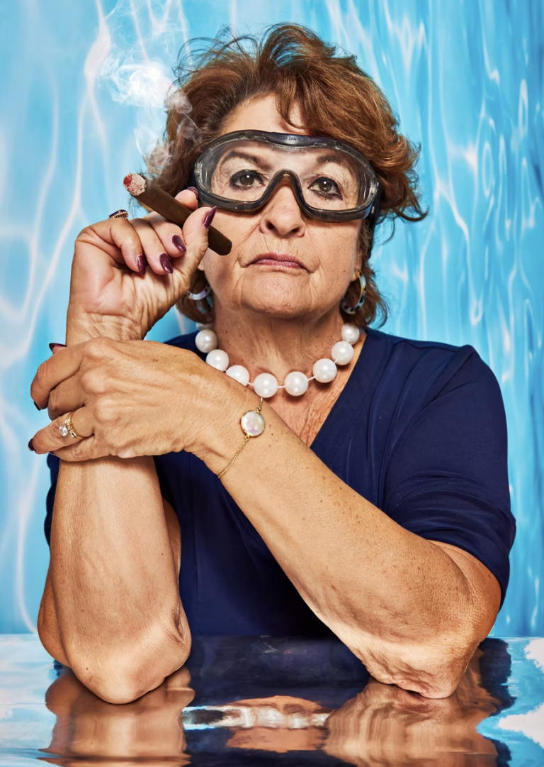 A woman wearing goggles and holding a cigar