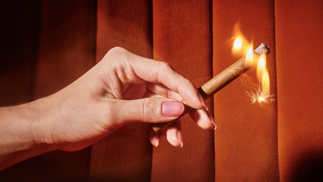 a hand holding a lit cigarette