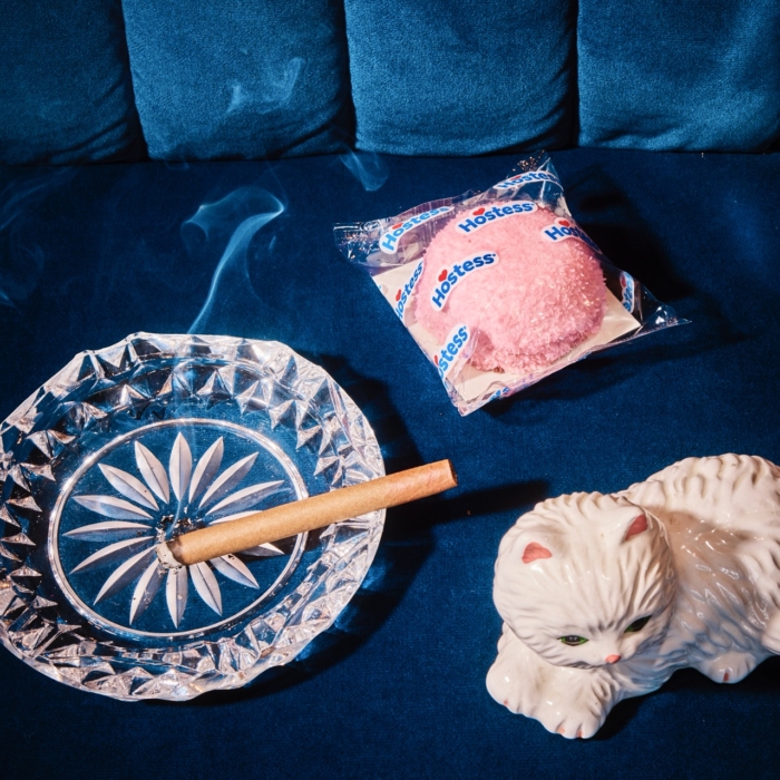 a cat figurine and a cigarette and a bag of pink frosted donut