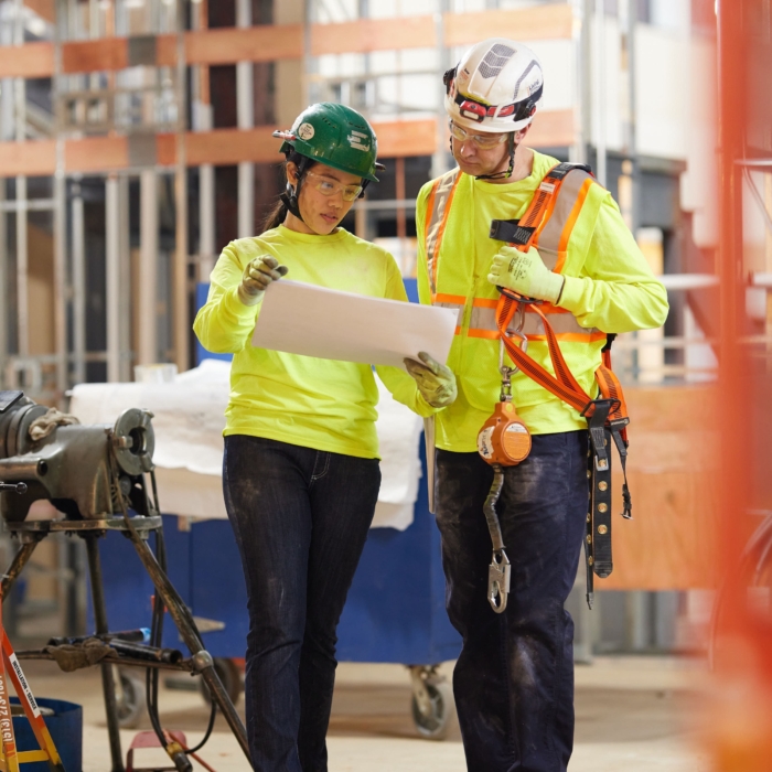 a man and woman in safety gear looking at a paper, Cintas, construction, workplace, jobsite, on location