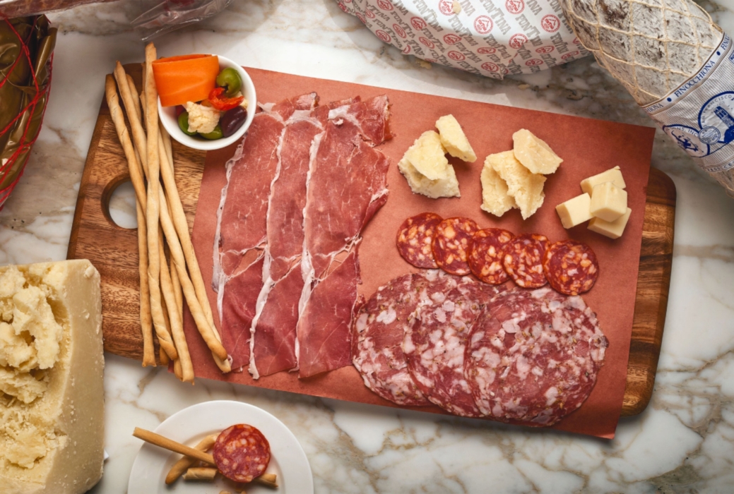 Overhead charcuterie spread with cured meats, cheeses, breadsticks, and pickled vegetables, photographed by OMS Photo, expert commercial food photographer.