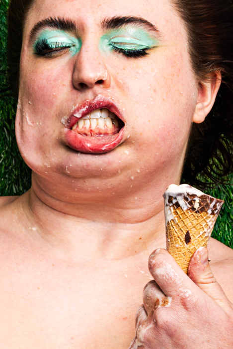 Close-up of a woman's smeared makeup and melting ice cream on her face as she holds a dripping cone.