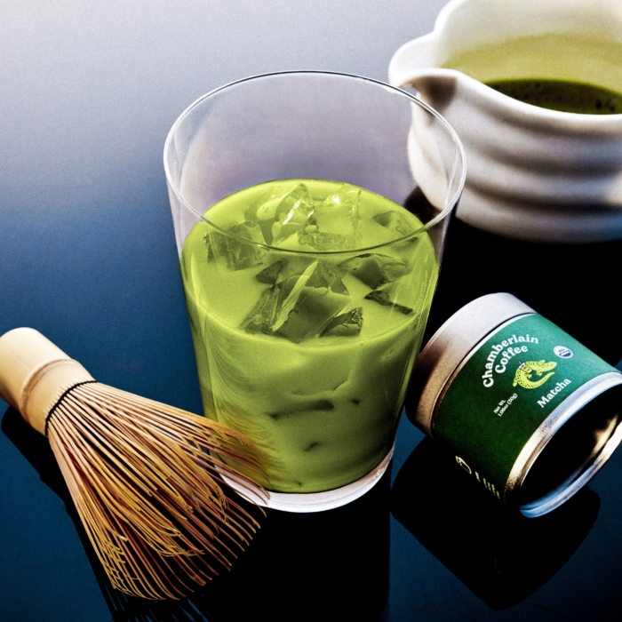 Green matcha latte with bamboo whisk and tea tin styled for premium commercial beverage photography