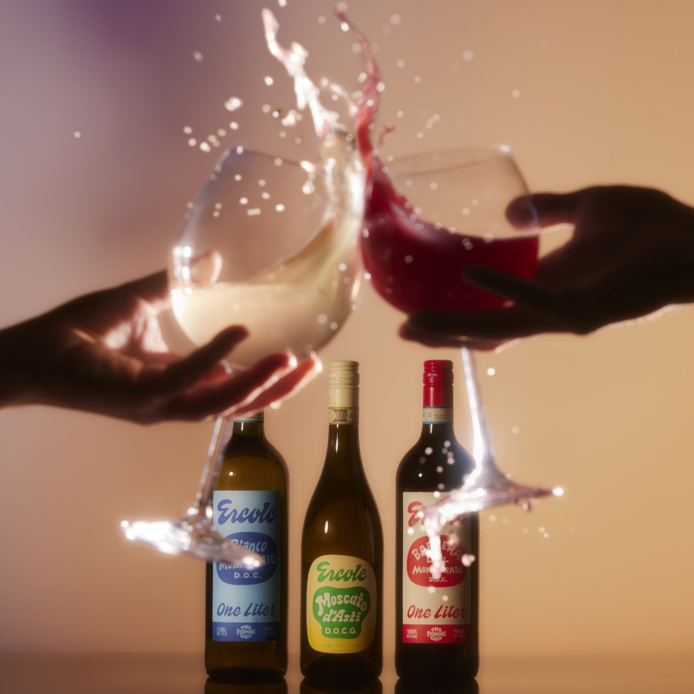 Two hands exchanging bottles with dramatic high-speed liquid splash captured in studio lighting