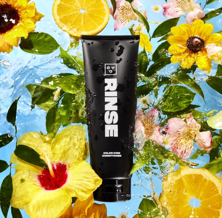 RINSE cosmetic cleanser photographed with fresh citrus slices, florals, and water splashes on a vibrant botanical background