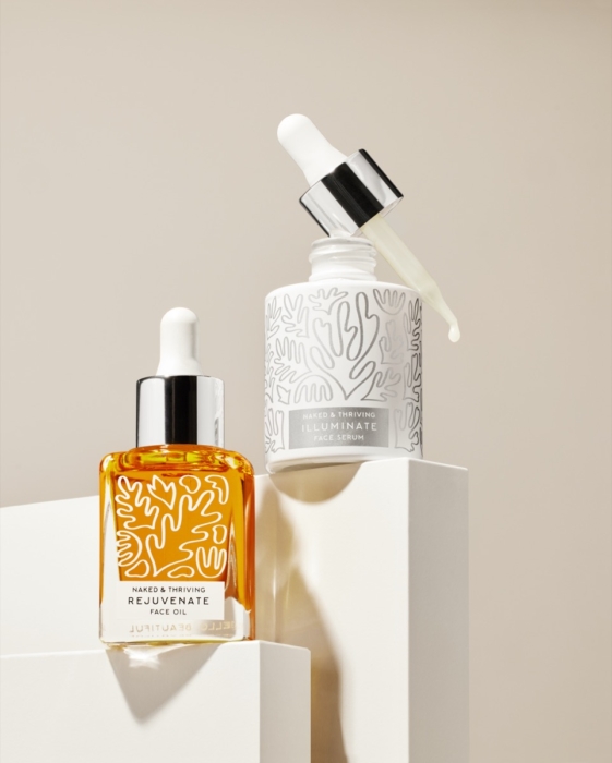 Naked & Thriving serum bottles photographed in warm sculptural lighting for commercial beauty campaign