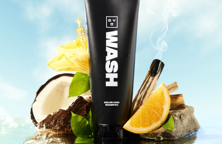 WASH cosmetic cleanser photographed with citrus, coconut, and water reflections on a clean aquatic surface