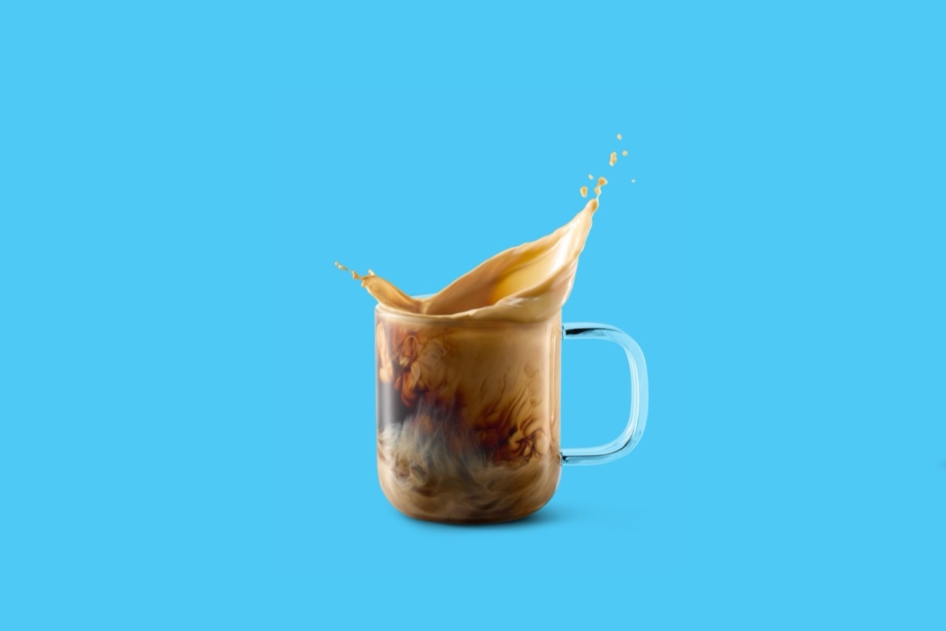 Minimal glass mug of iced coffee with Horizon Organic creamer splash frozen mid-air.